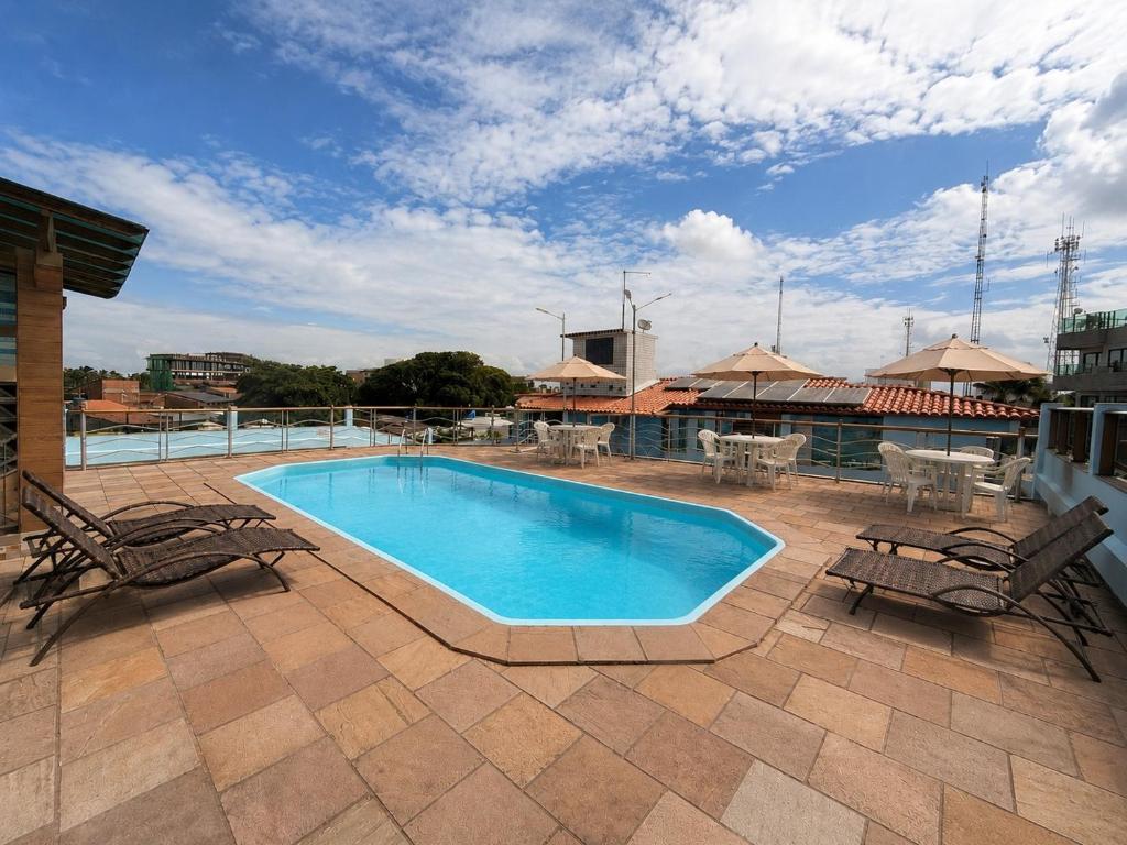 a swimming pool on a patio with chairs and tables at Pousada Recifes de Corais in Porto De Galinhas