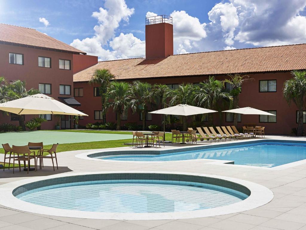 a resort with a pool and tables and chairs at Novotel Campo Grande in Campo Grande