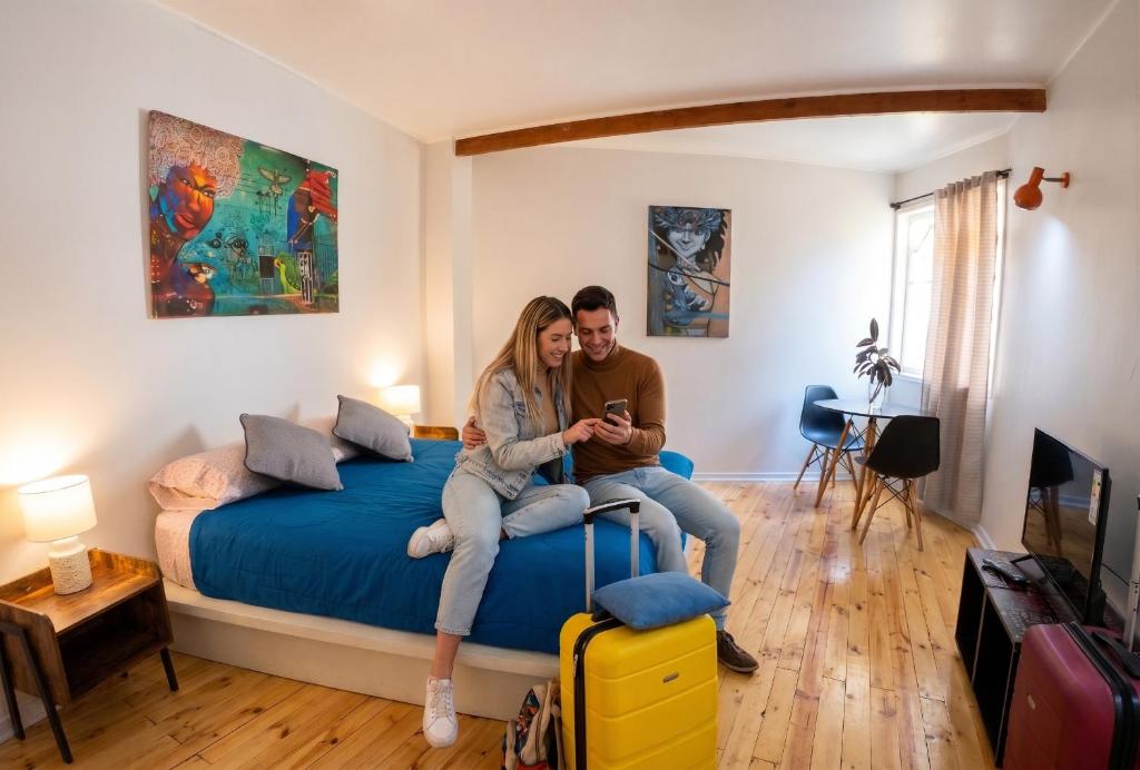 a man and a woman sitting on a bed at Escarabajo Hostel in Valparaíso