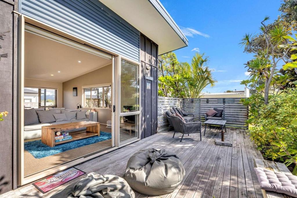 a home with a deck with a living room at Fun on the Fairway in Matarangi