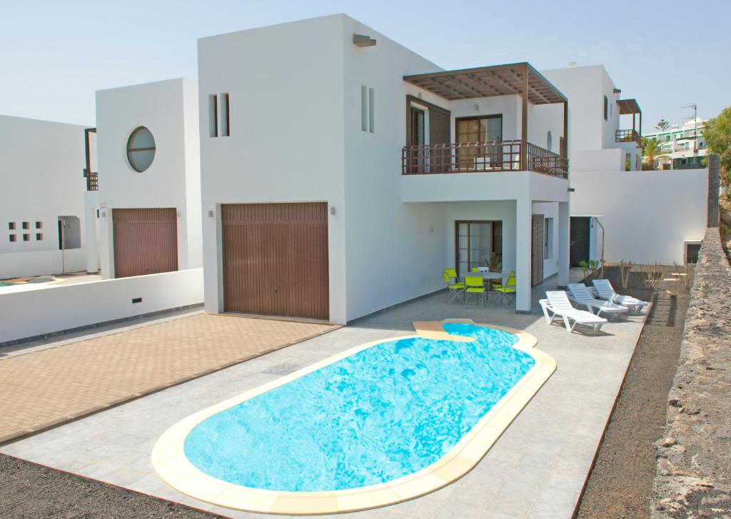 Villa con piscina frente a una casa en Villas Las Maretas, en Costa Teguise