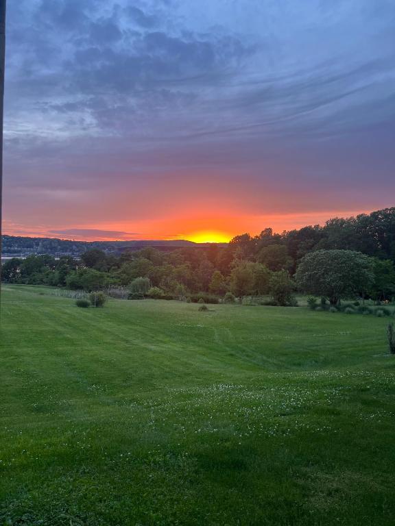 a sunset in a field with a field of grass at Beacon Hudson Hideaway in Beacon