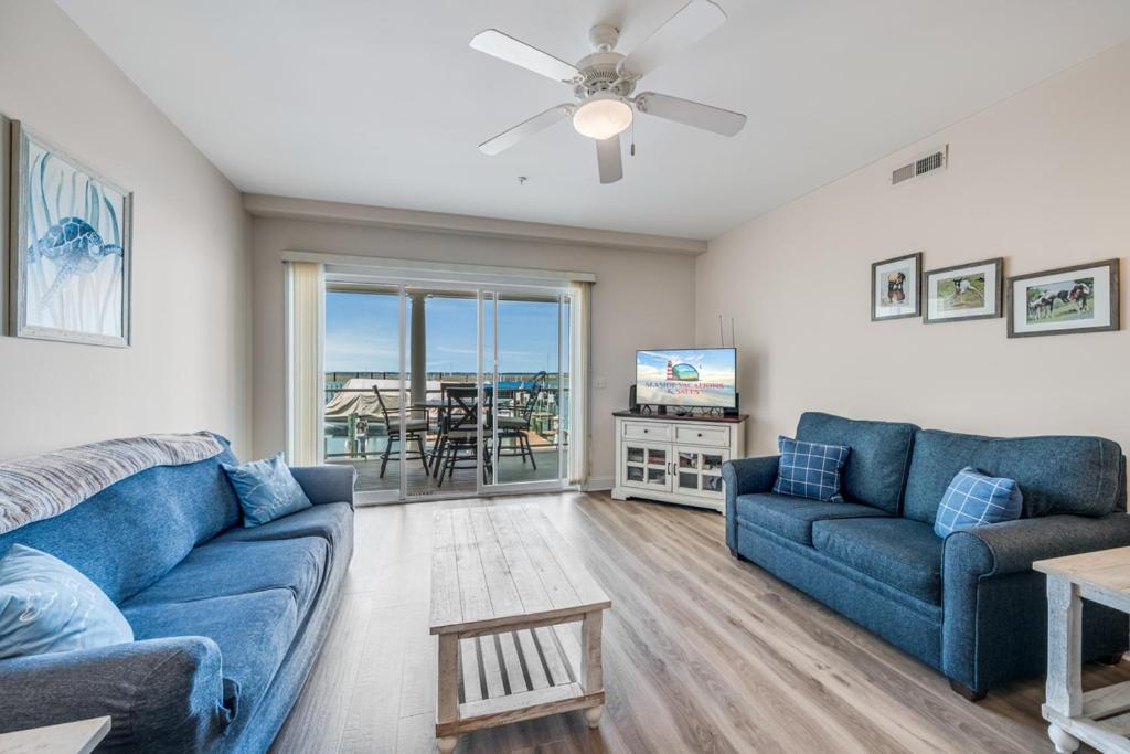 a living room with two blue couches and a television at Sunset Bay Villa 110 - Hawks Nest in Chincoteague