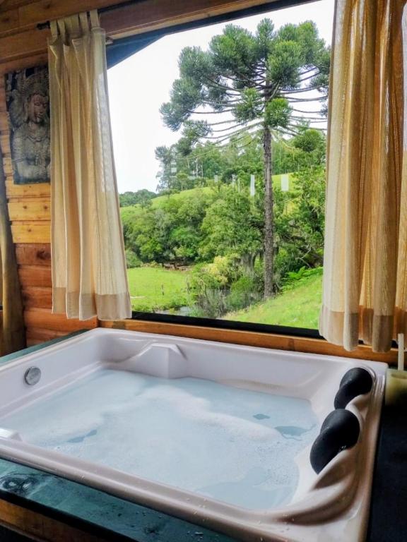 a bath tub in a room with a window at De oio no arroio in Cambará