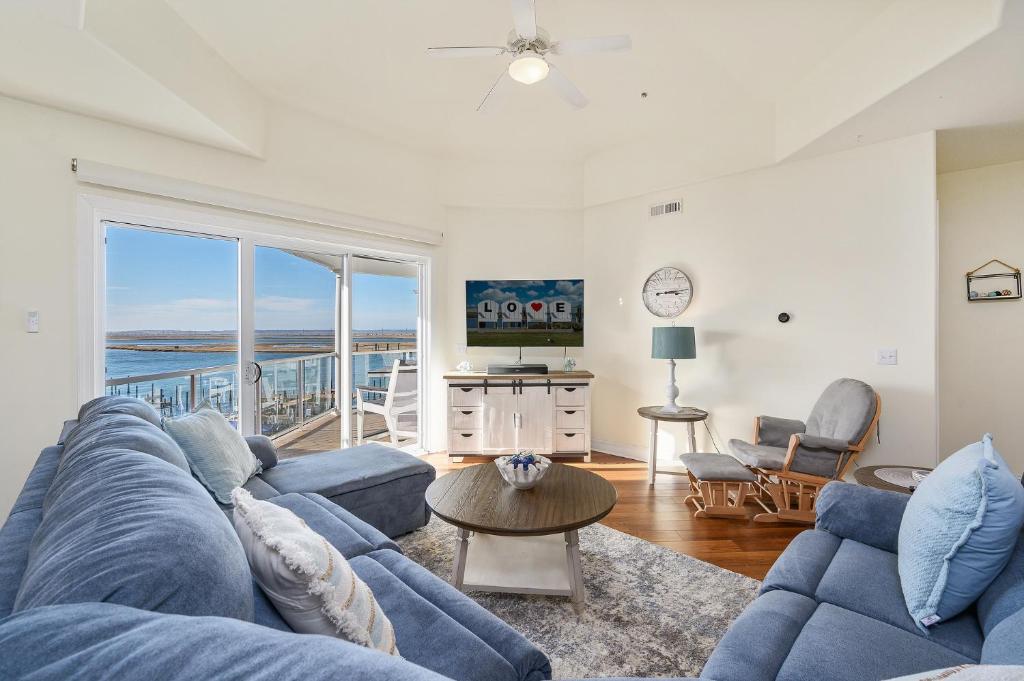 a living room with a blue couch and a view of the ocean at Sunset Bay Villa 313 - By the Bay in Chincoteague