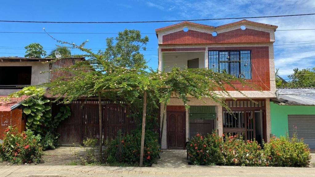 a house with a tree in front of it at Milflora casa completa in Nuquí