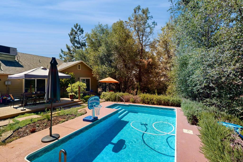 a swimming pool with an umbrella next to a house at 1 Mi to Lake Tulloch: Home w/ Patio Oasis & Pool in Copper Cove Subdivision
