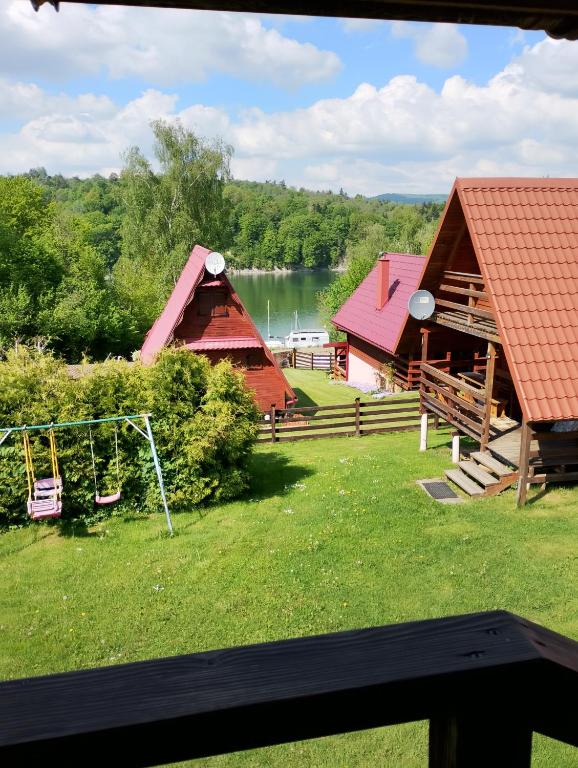 a view of a house with a playground and a lake at Domek Olchowiec 2 Nad Soliną in Olchowiec