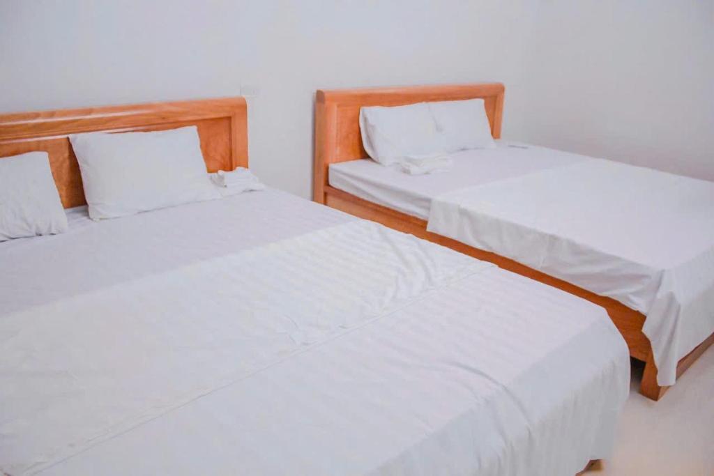 two beds with white sheets in a room at Tám bảy in Cửa Lô