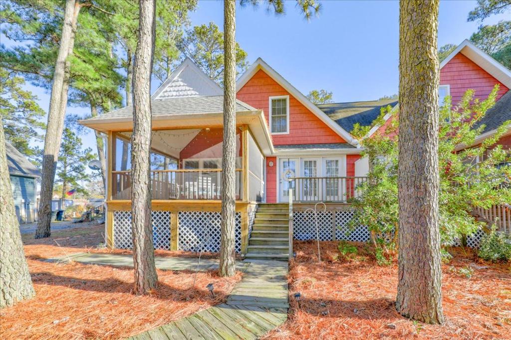 a red house with a porch in the woods at Whispering Pines in Black Point Landing