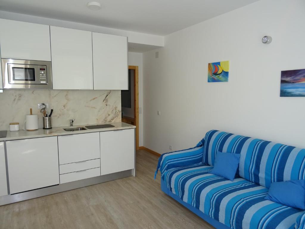 a living room with a blue couch and a kitchen at Casa do Bairro in Sesimbra