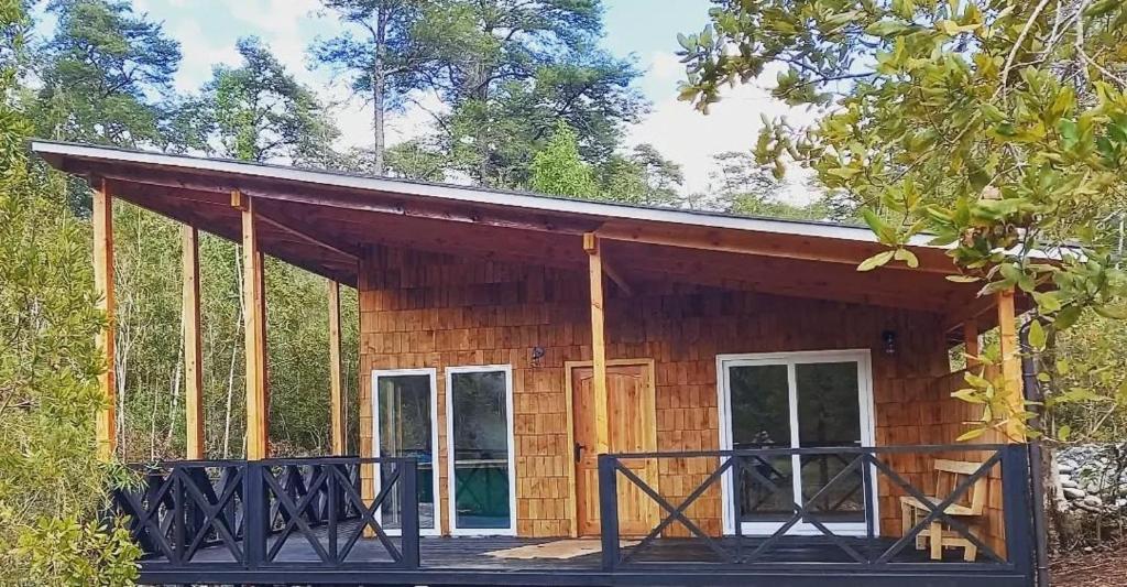 a log cabin with a porch in the woods at Entre Bosque Puelo in Puelo