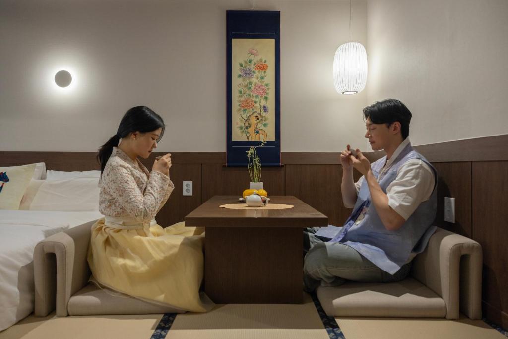 a man and woman sitting at a table in a hotel room at Onjae Stay Seongsu in Seoul