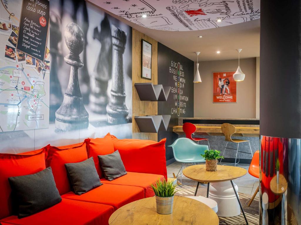 a living room with a red couch and tables at Ibis Bilbao Barakaldo in Barakaldo