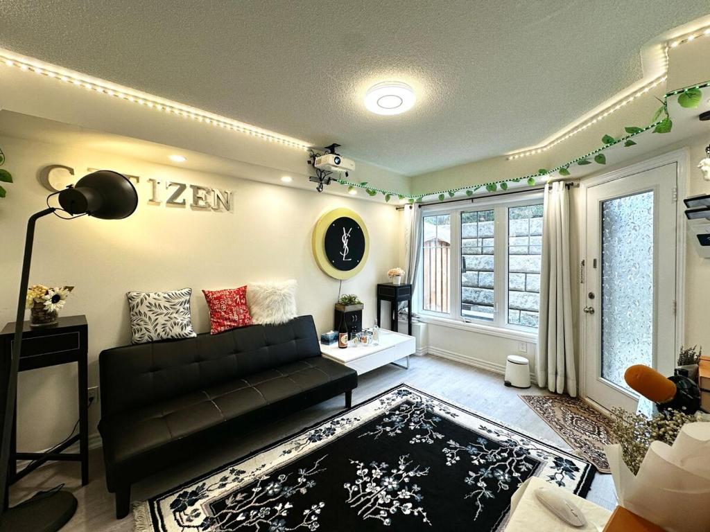 a living room with a black couch and a window at Comfortable 2BR Getaway with Extra Lounge Space in Toronto