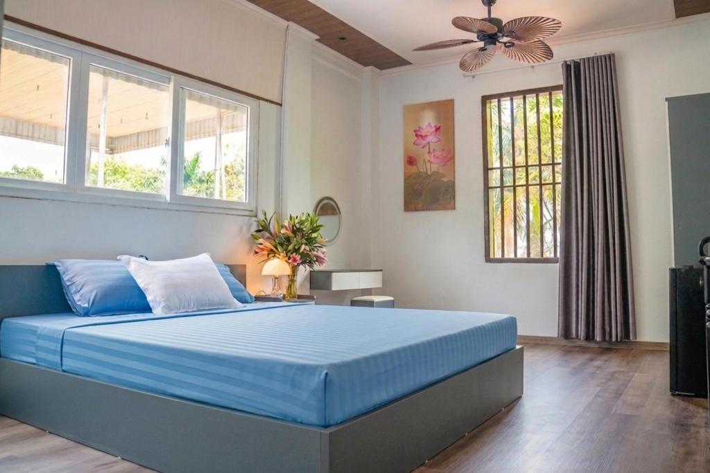 a bedroom with a blue bed and windows at Favos Bích Động in Vũ Lâm