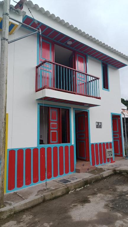 a white building with red doors and a balcony at apartamento vacacional red 1 in Salento