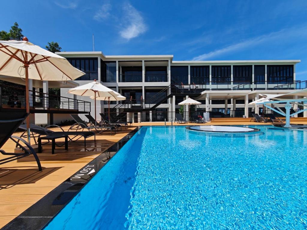 a large swimming pool with umbrellas next to a building at Karon Utopia in Karon Beach