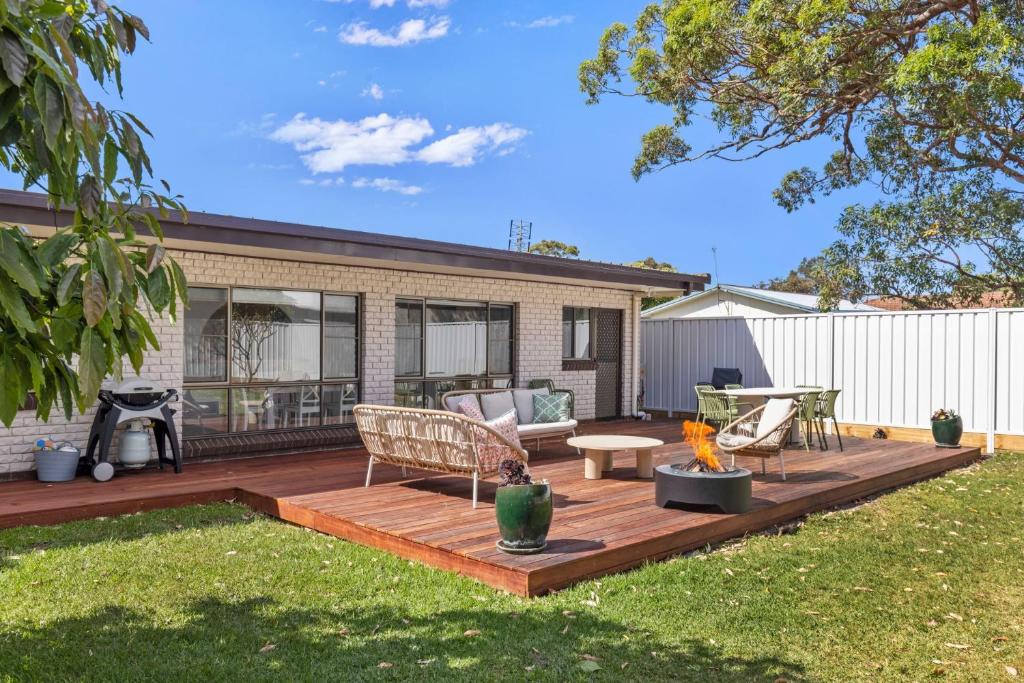 a deck with a couch and chairs on a yard at Coastline Callala - Fire Pit - Pet Friendly in Callala Beach