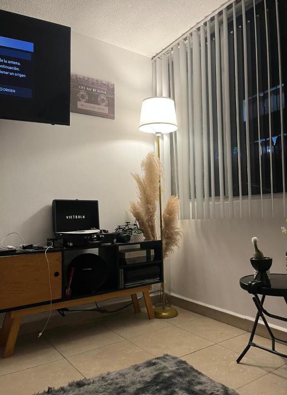 a living room with a desk with a computer and a lamp at Lagom 406 Habitación en depa duplex in Mexico City