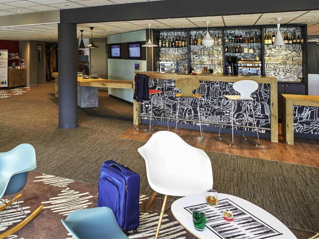 a waiting area with chairs and a bar in an office at Ibis Auray in Auray