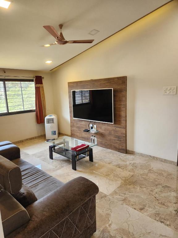 a living room with a couch and a flat screen tv at Castel Rock in Nashik