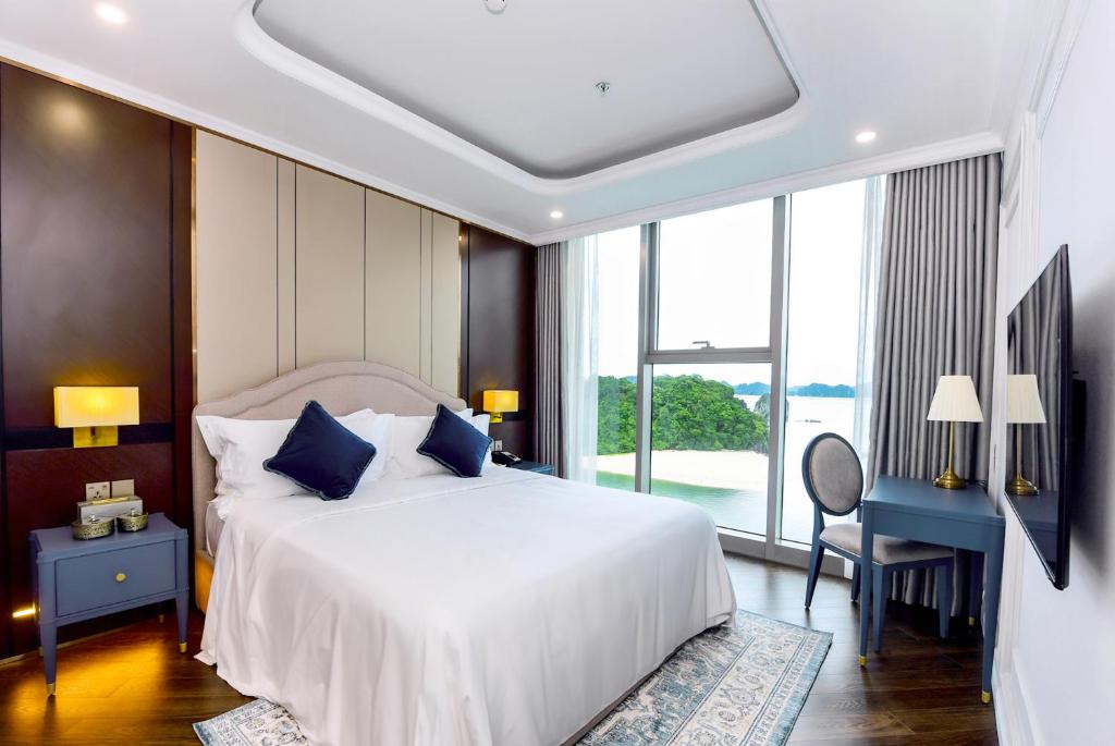 a bedroom with a large white bed with blue pillows at Centara Hotel & Residences Van Don in Cái Rồng