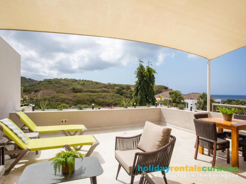 a patio with chairs and tables and a view of the ocean at Apartment 387 Blue Bay in Dorp Sint Michiel