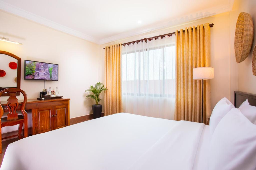 a bedroom with a white bed and a window at Apsor Villa in Phumĭ Réach Born (2)