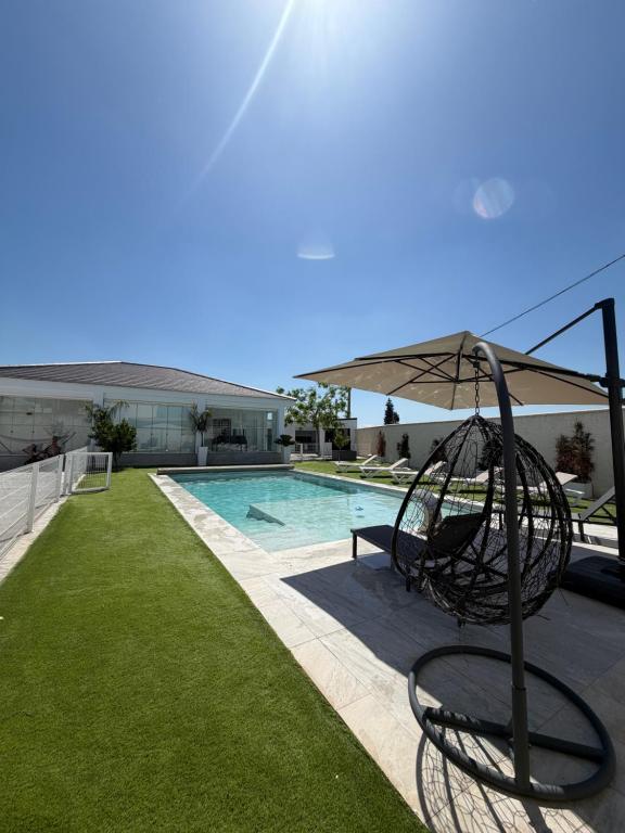 a swimming pool with a chair and an umbrella at Chalet Escapada in Seville