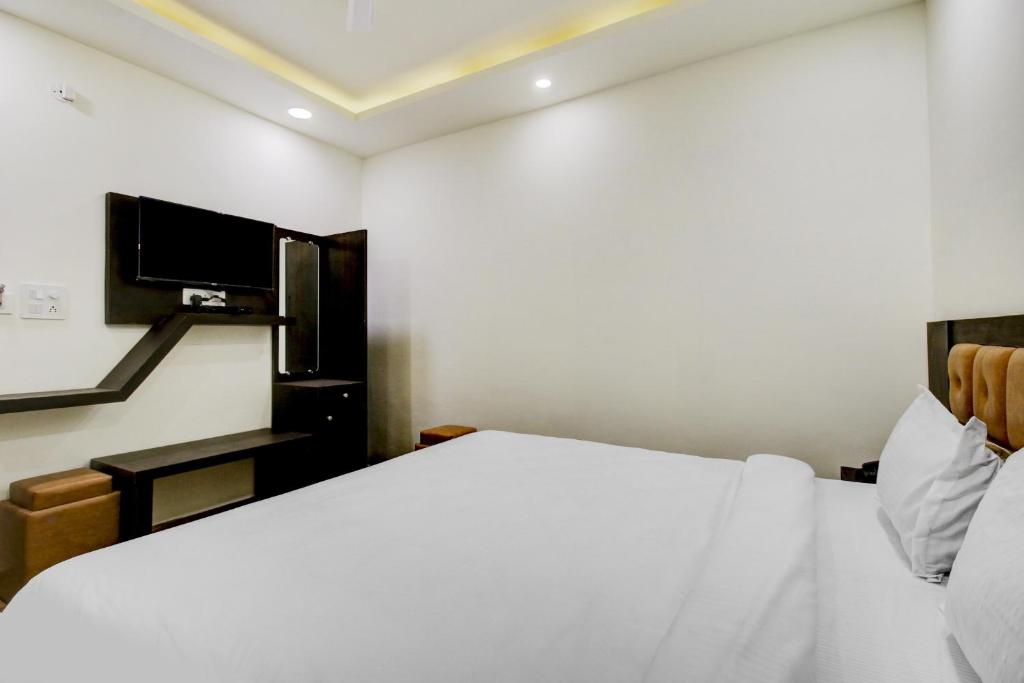 a bedroom with a white bed and a tv at Hotel O Bonsai in Bhopal