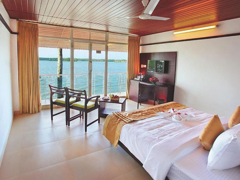 a bedroom with a large bed with a view of the ocean at Mannath Ayur Island Resort in Murinjupuzha