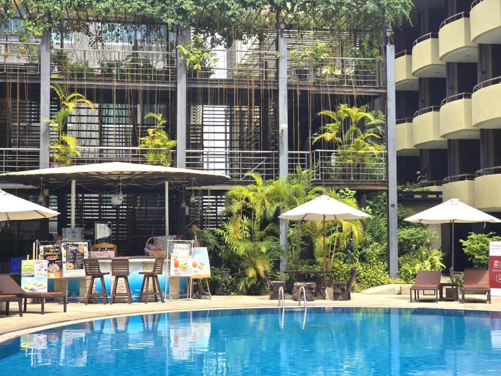 a swimming pool with chairs and umbrellas in a building at Baron Beach Hotel in Pattaya
