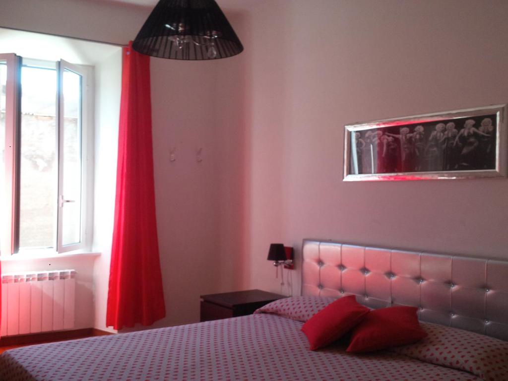 a bedroom with a bed with a red curtain and a window at Magic Stefy's Rooms in Rome