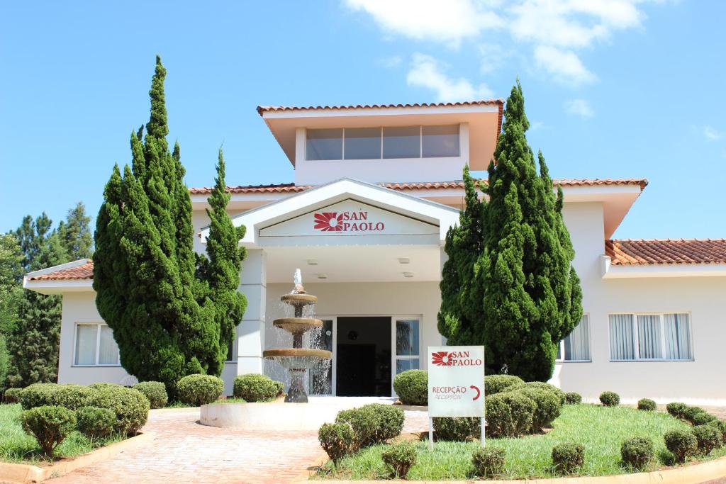 a building with a fountain and trees in front of it at Hotel San Paolo in Pederneiras