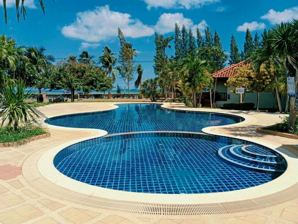a swimming pool in a resort with palm trees at Sailom Resort Bangsaphan in Bang Saphan