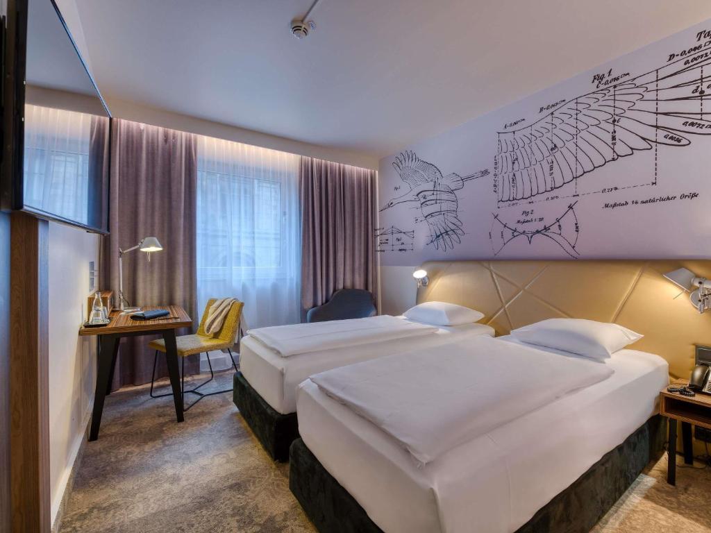a hotel room with two beds and a desk at Mercure Hotel Berlin City in Berlin