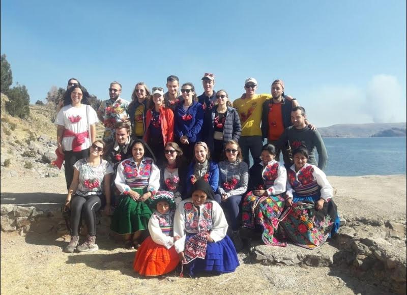 a group of people posing for a picture on the beach at Lake HOME in Puno