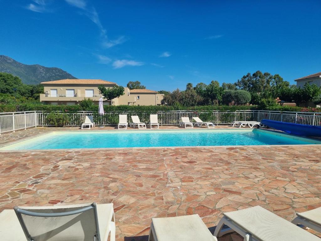a swimming pool with chairs and a house at Mini Villa 200 m de la plage in Cervione