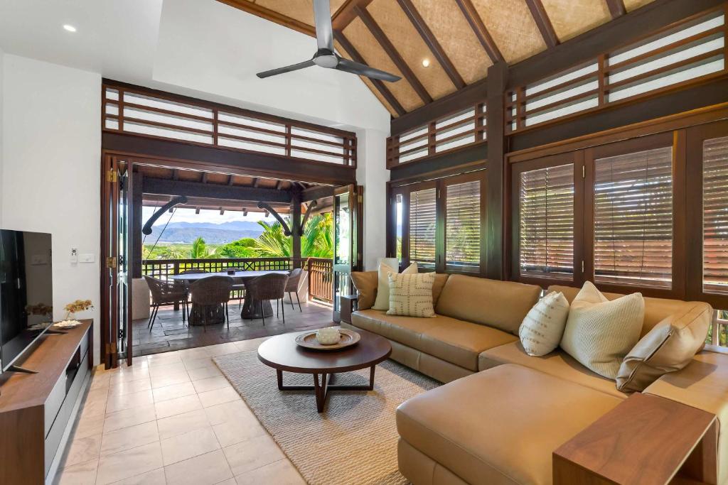 a living room with a couch and a table at Monsoon Villa A - Central Balinese-style Pool Oasis in Port Douglas