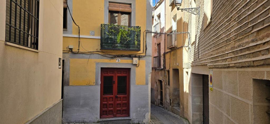 a narrow alley with a red door and buildings at apto La Campana in Toledo