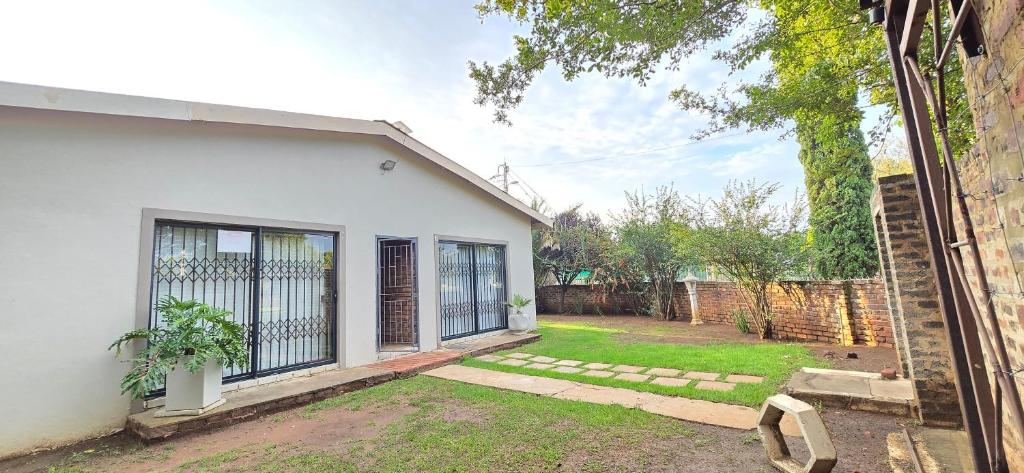 a white house with a gate and a yard at Co operville in Potchefstroom
