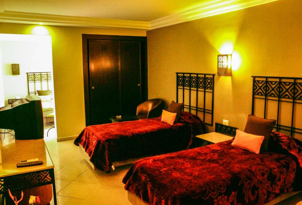 a hotel room with two beds and a chair at Hotel Continental in Kairouan