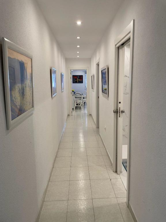 a hallway with white walls and a long hallway with paintings at Anna Apartment in Altea