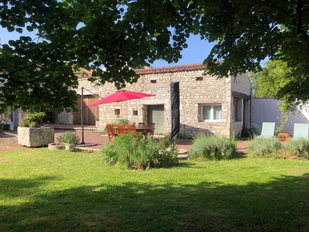 a brick house with a red umbrella in a yard at Gite La Saintonge in Sainte-Gemme