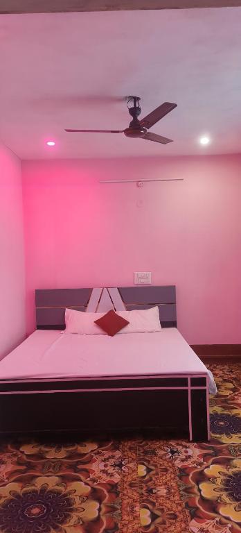 a pink room with a bed with a ceiling fan at Hotel Sunrise inn in Nārdiganj