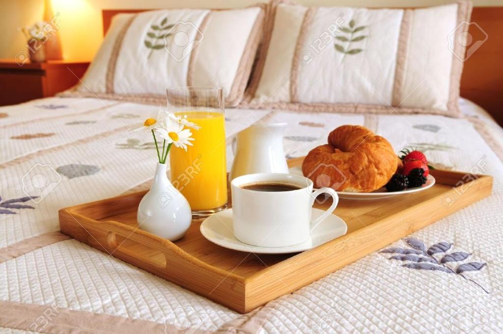 a tray with a cup of coffee and a plate of food on a bed at Hotel Guľa in Batizovce