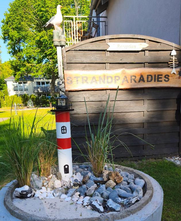 a garden with a red and white pole and a sign at Ferienwohnung Strandparadies 7 in Juliusruh