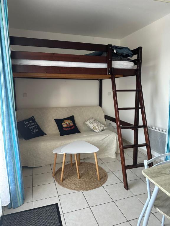 a room with a bunk bed and a couch and a stool at Gite aux grès des vents in Champeaux