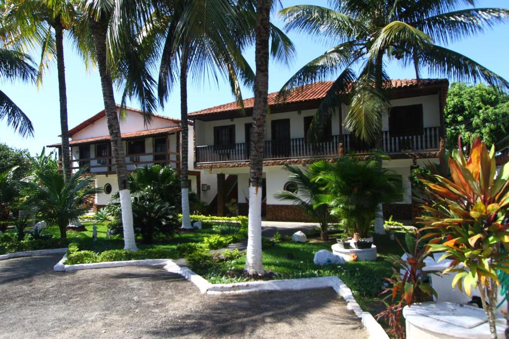 a house with palm trees in front of it at Pousada Calvanos Chalés in Rio das Ostras